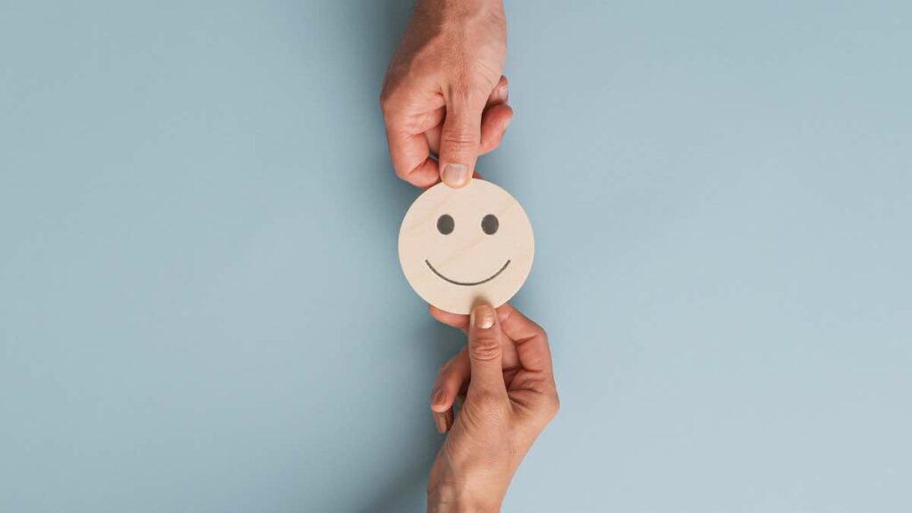 Two hands holding smiling face button over a table