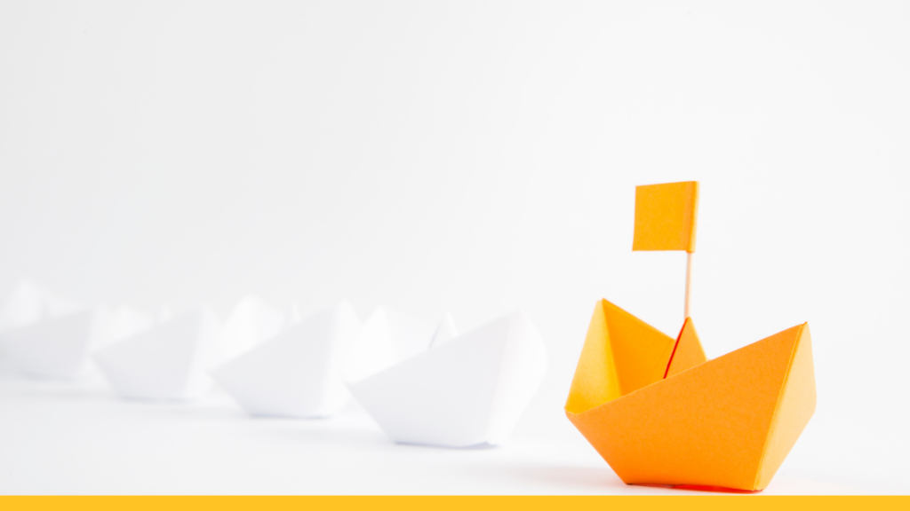 a yellow paper boat leads a line of white paper boats behind it