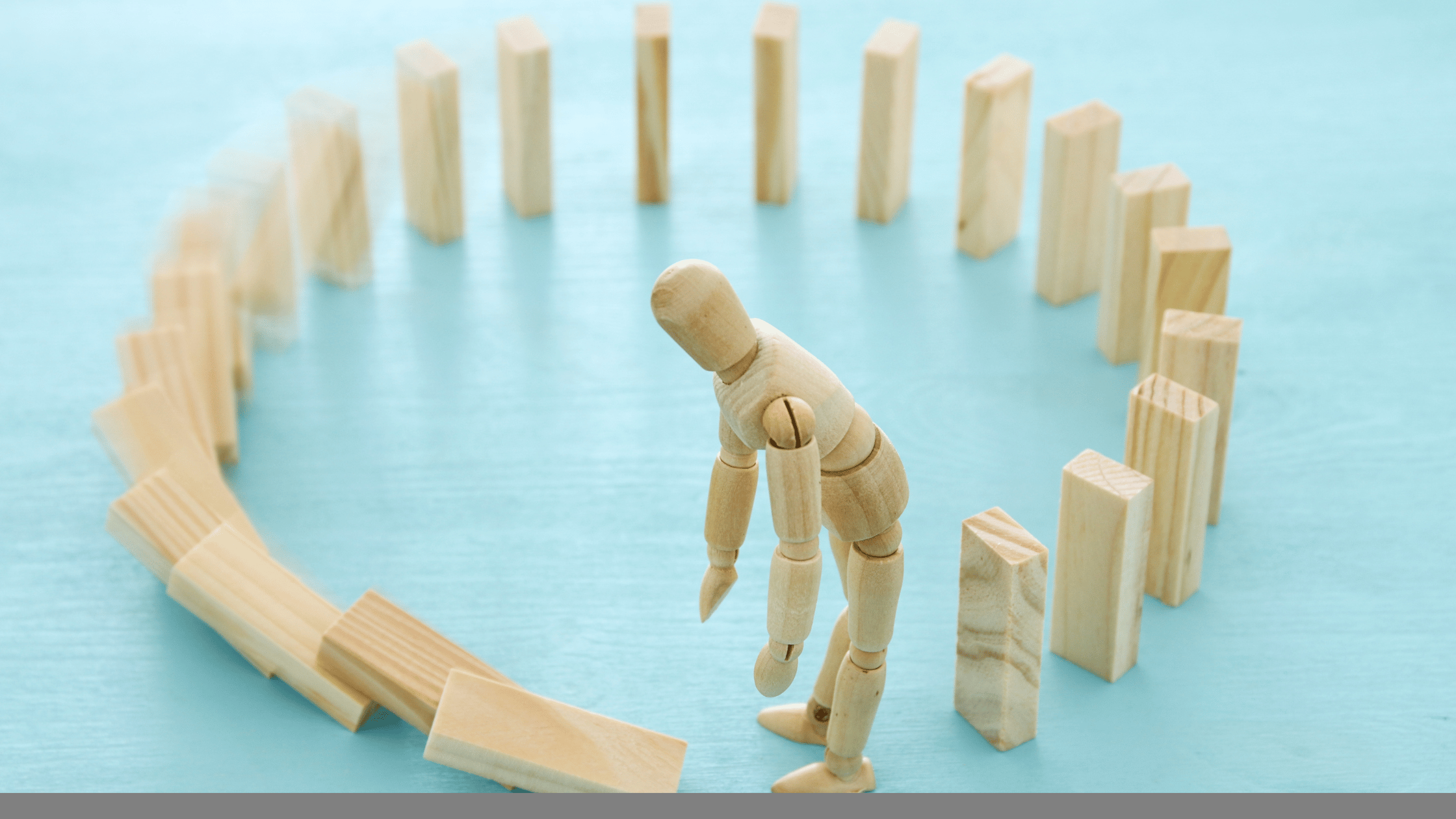 wooden figure pushing down a row of blocks