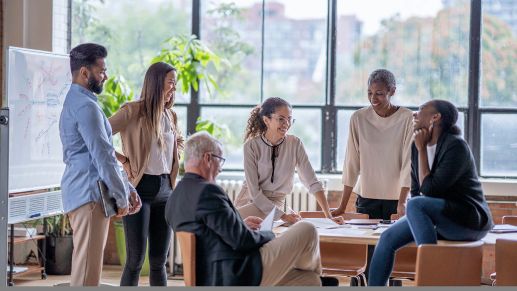 a diverse group of coworkers sits around a conference table