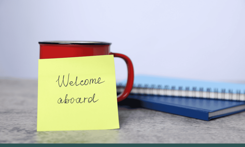 A coffee mug with a post it note that reads welcome aboard